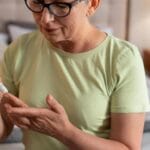 Mujer adulta realizándose una prueba de glucosa en sangre para detectar diabetes. La imagen muestra a la señora mirando su dedo mientras recibe asistencia para la prueba, simbolizando la importancia de los chequeos preventivos en el control de la diabetes.